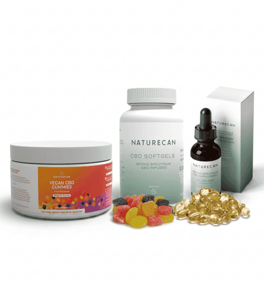 Naturecan CBD wellness kit featuring a jar of vegan CBD gummies, a bottle of broad spectrum CBD oil, a dropper bottle, a box, and loose gummy and softgel capsules on a white background.